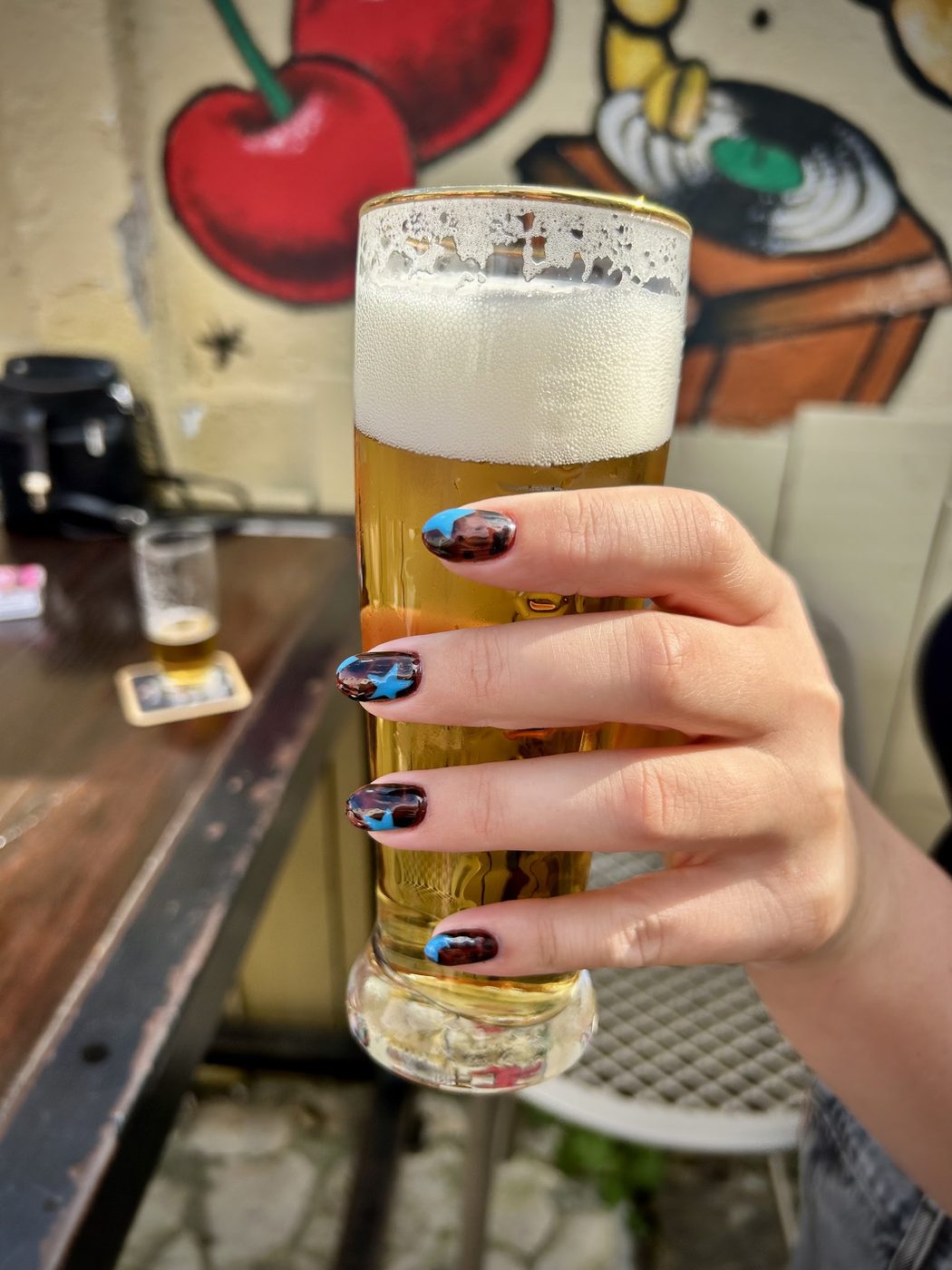 Hand met kleurrijke nail art om een glas bier