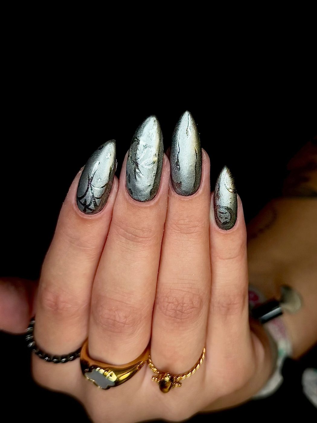 Zilveren chrome stiletto nagels op een zwarte achtergrond